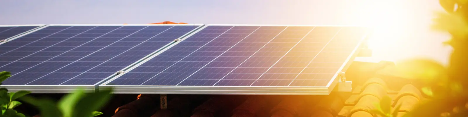 Solar panels on a residential roof with the sun setting in the background