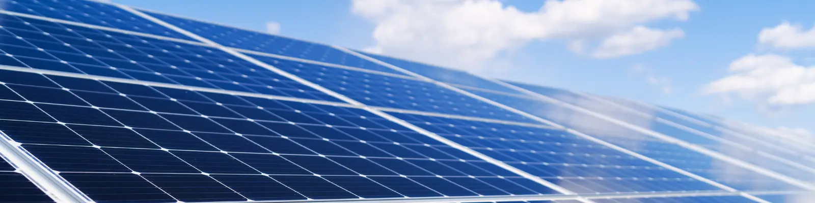 Solar panels in the foreground with blue cloudy sky behind